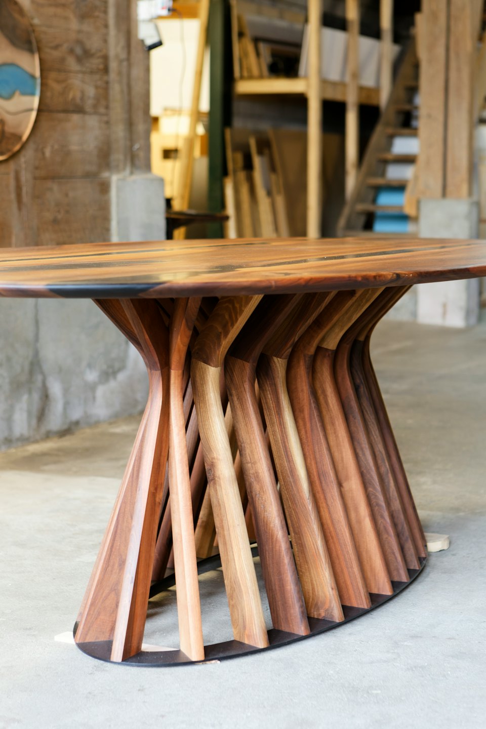 Sculptural wooden table with intricate base in studio.