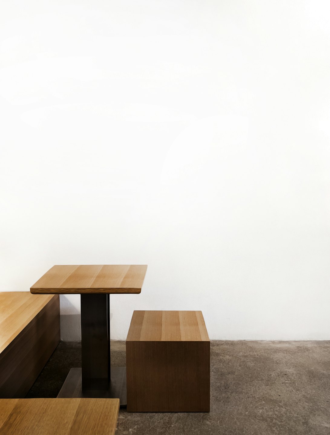 Contemporary wooden furniture pieces sit on a grey concrete floor.