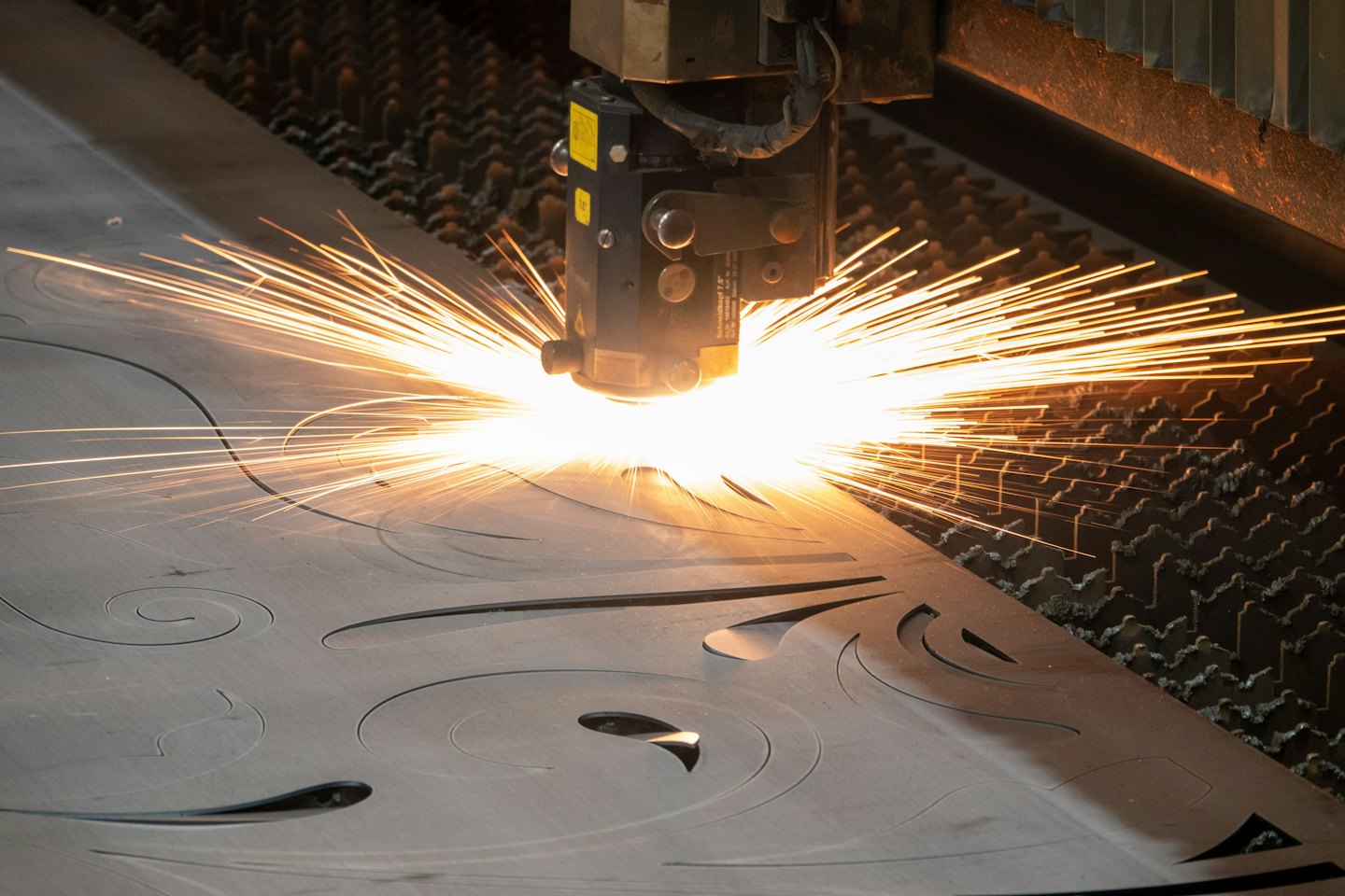 Industrial laser cutter carves intricate patterns into metal sheet.
